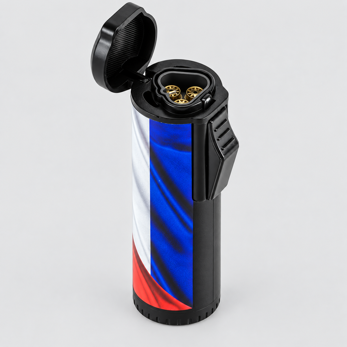 A cylindrical lighter with a black plastic body and lid, featuring a printed cuba flag design on the main body. The lighter is shown open, revealing gold-toned ignition components inside, set against a plain light gray background.