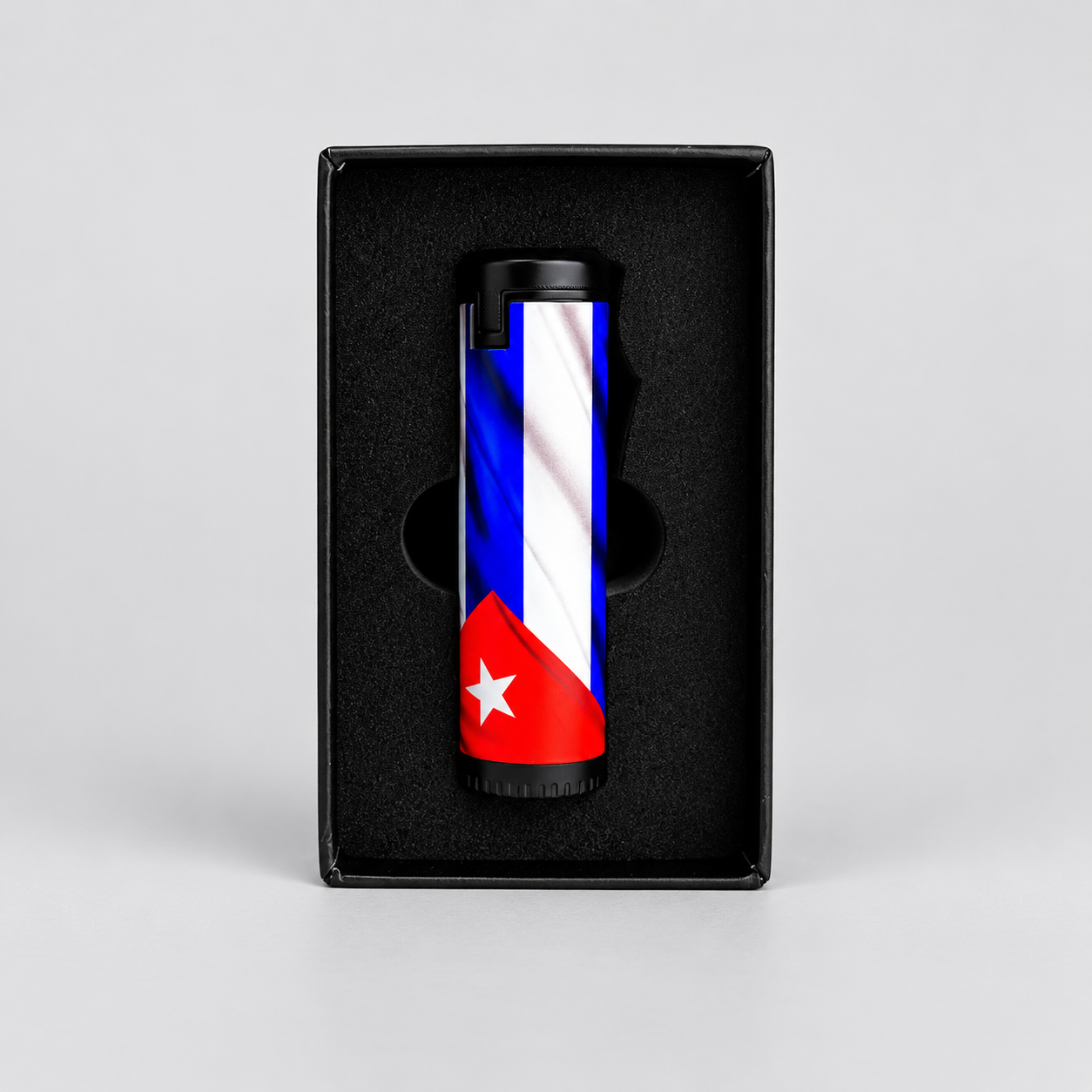 A cylindrical lighter with a Cuban flag design, presented inside a black gift box on a light gray background.