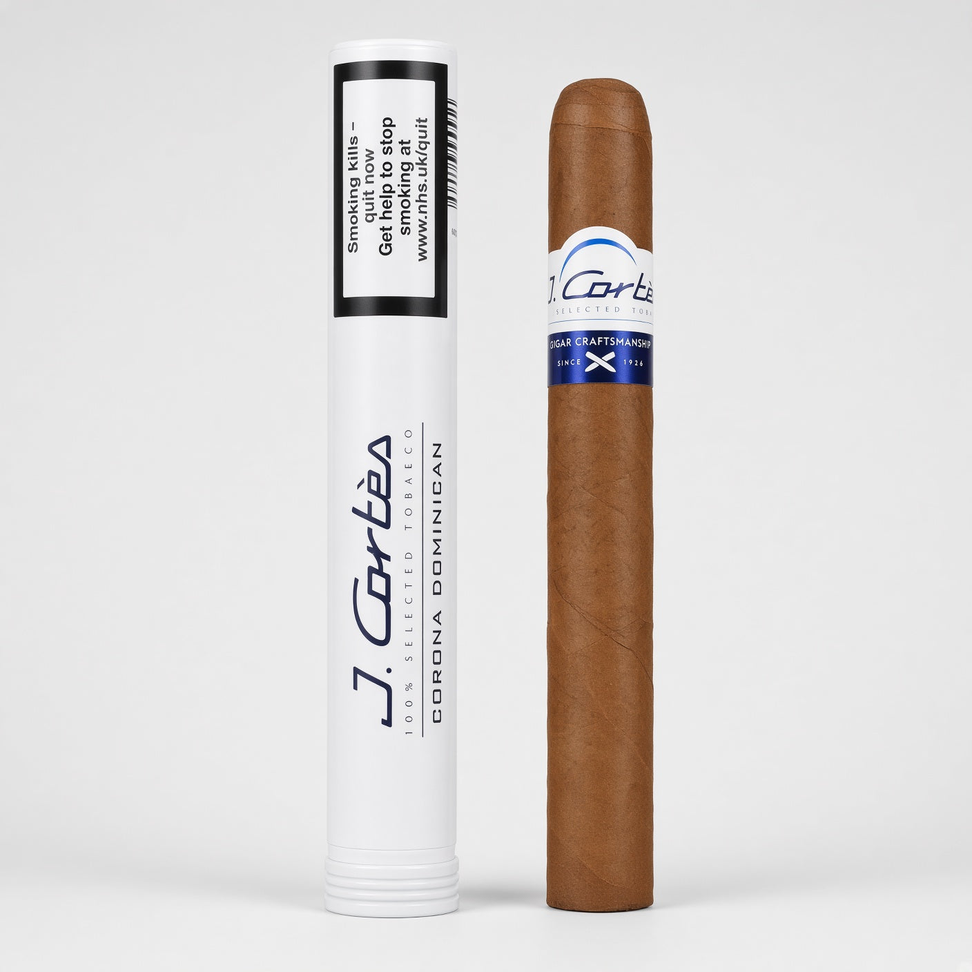 A single brown cigar shown upright next to its white cylindrical packaging tube on a light gray studio background. The tube has black and blue text, including the brand name J.