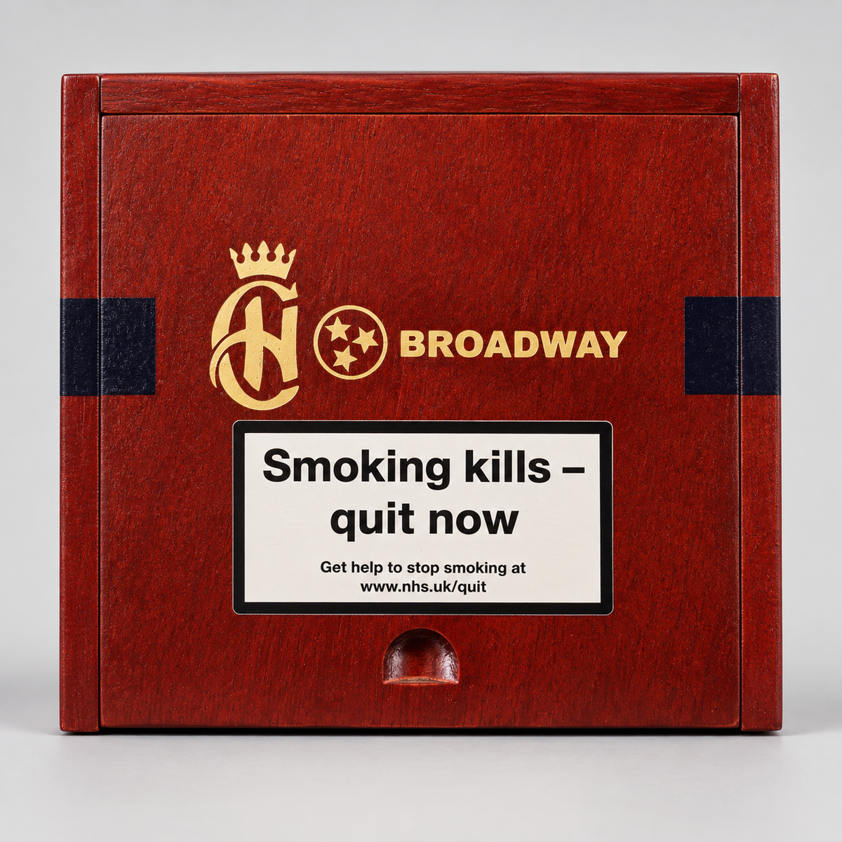 A rectangular wooden box with a reddish-brown woodgrain finish, featuring gold and black branding that reads 'AH' with a crown and 'BROADWAY'. A large white warning label on the front reads 'Smoking kills - quit now' with smaller smoking-cessation text below.