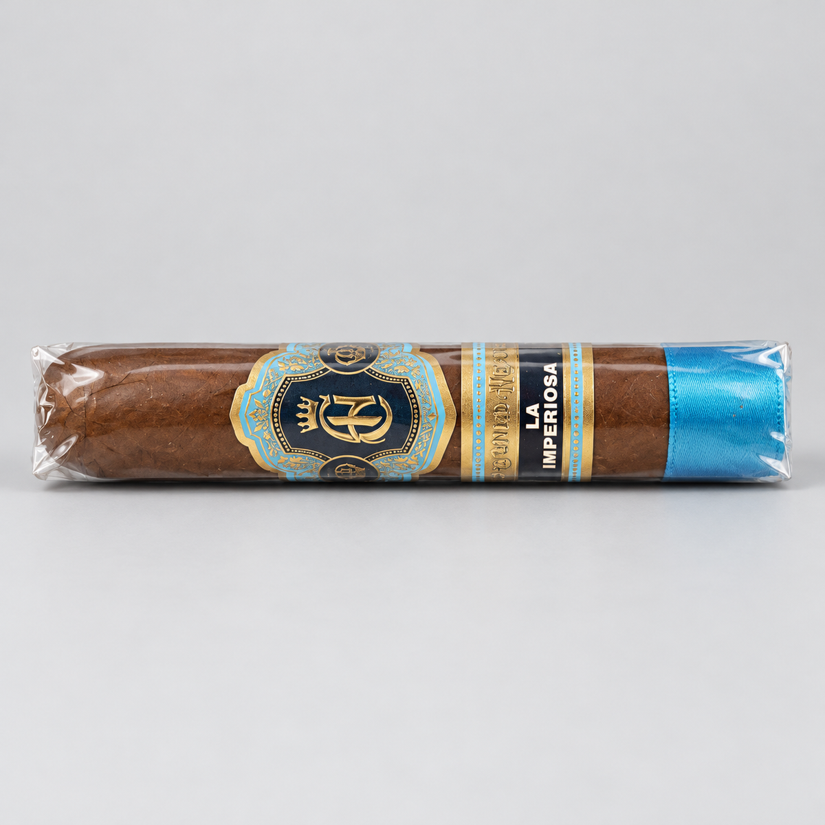 A single wrapped cigar on a light gray background. The cigar is brown with a decorative label featuring gold, blue, and black details, and a bright blue band at the end.