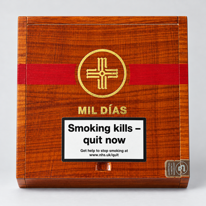 A rectangular wooden box with a warm reddish-brown woodgrain finish, a bold red horizontal band, and a gold circular cross-like emblem. The front also shows the text 'MIL DÍAS' and a large white warning label reading 'Smoking kills - quit now' with smaller quit-smoking contact text.