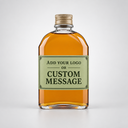 A customizable glass bottle with amber liquid, a gold screw cap, and a light green label that reads 'ADD YOUR LOGO OR CUSTOM MESSAGE', centered on a light gray background.