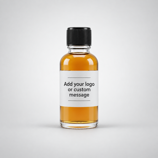 A small clear glass bottle with a black ribbed cap and a white label reading 'Add your logo or custom message,' filled with amber liquid, centered on a light gray background.