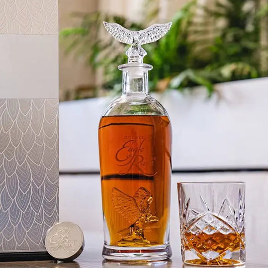 Glass decanter with whiskey and a glass on a table with decorative elements.
