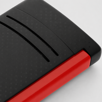 Close-up of a black textured rectangular product with a bright red side edge, photographed on a clean light gray background.
