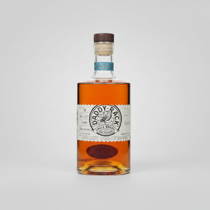A bottle of Daddy-Rack Single Barrel bourbon whiskey with amber liquid, a white paper label, and a brown cork stopper, shown on a white background with a soft reflection.