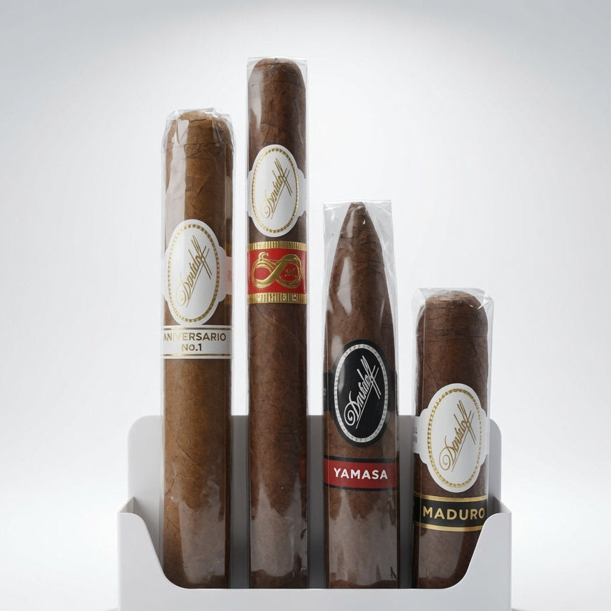 Four Davidoff cigars in a white plastic display stand against a light gray studio background. The cigars are wrapped in brown paper with white, red, and black labels, including visible text such as Anniversary, Yamasa, and Maduro.