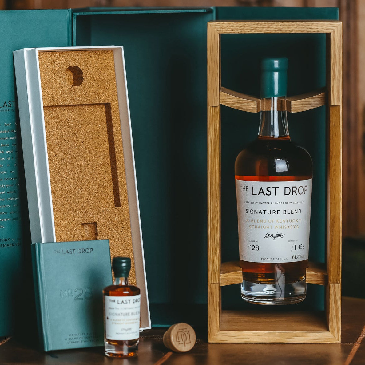 Bottle of 'The Last Drop' whiskey in a wooden box with a cork stopper on a wooden surface.