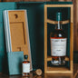 Bottle of 'The Last Drop' whiskey in a wooden box with a cork stopper on a wooden surface.