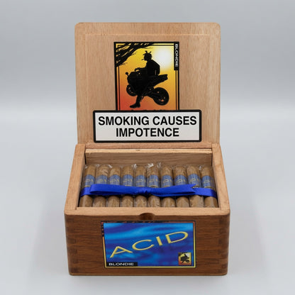 An open wooden cigar box on a light gray background, showing several cigars inside with blue bands and a front label reading ACID BLONDIE. The inside lid has a smoking warning sign and a small vertical brand mark that appears to read Cigarro.
