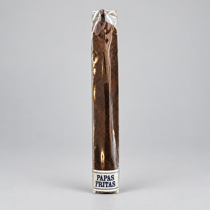 A single long cigar in a clear wrapper with a white band at the base reading 'PAPAS FRITAS', photographed upright on a light gray studio background.
