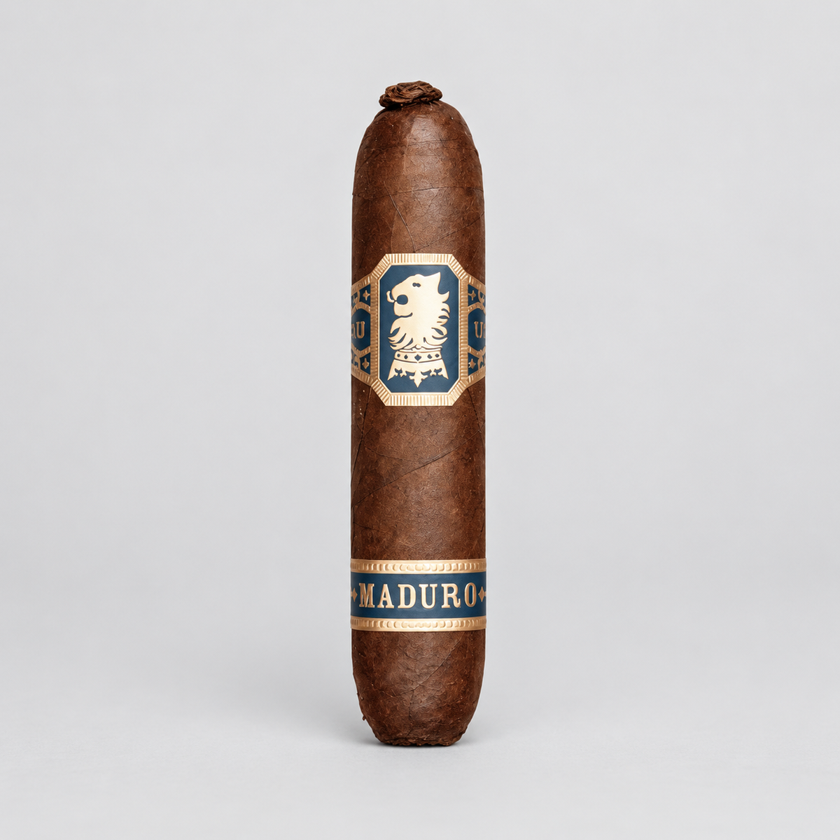 A single brown cigar standing upright on a light gray studio background, featuring a central blue and gold label with a lion emblem and the word 'MADURO' near the bottom.