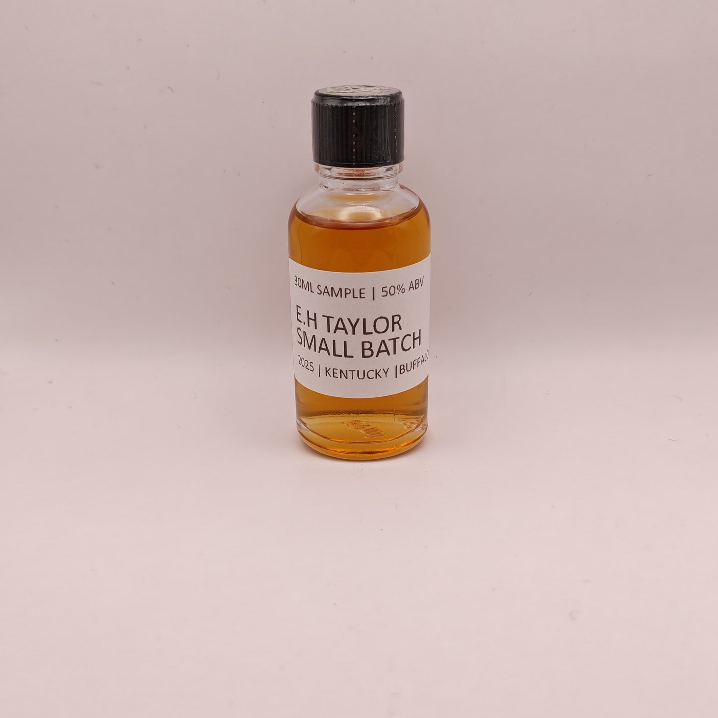 Small bottle of E.H. Taylor Small Batch whiskey on a beige background