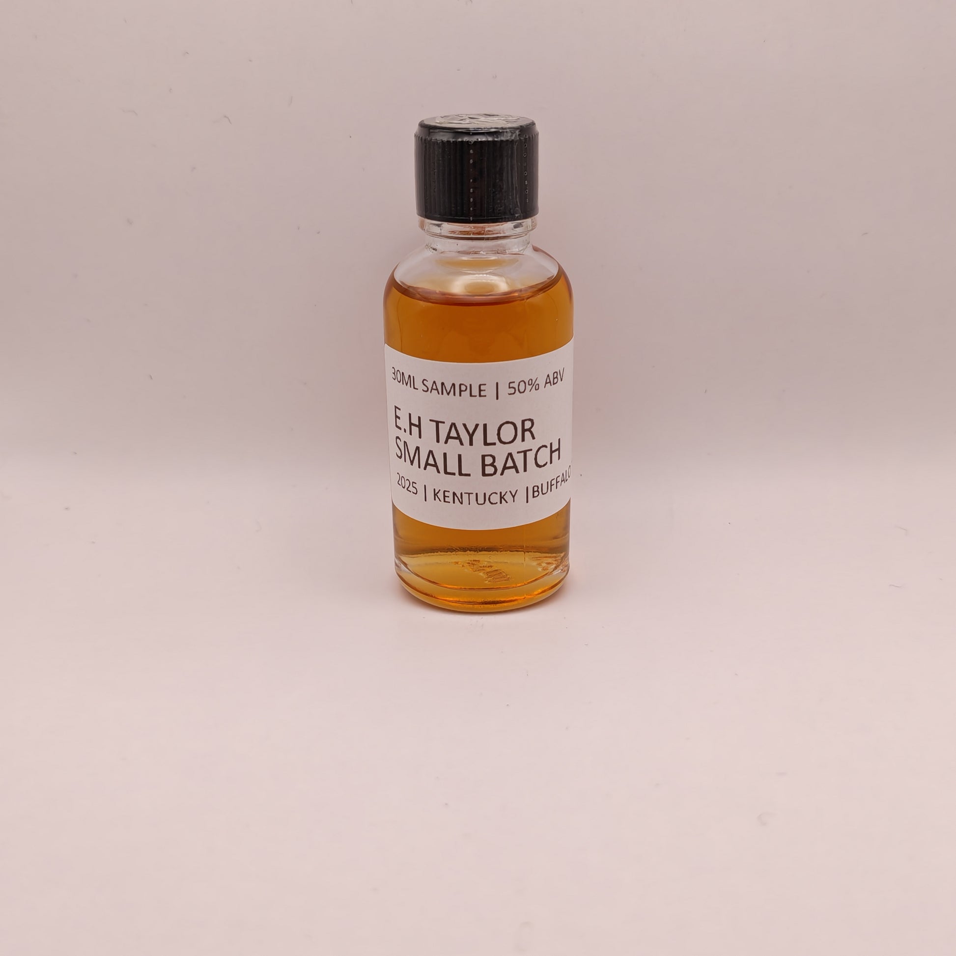 Small bottle of E.H. Taylor Small Batch whiskey on a beige background