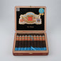 An open wooden cigar box on a light gray studio background, containing ten cigars. The interior lid is black with a large decorative La Historica crest and a blue cigar award seal.