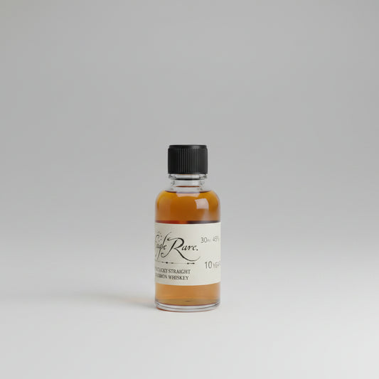 Small bottle of whiskey labeled 'Eagle Rare' on a bar counter with a blurred bar background