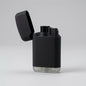 A matte black electronic lighter with its lid open, standing on a light gray surface against a neutral gray background.