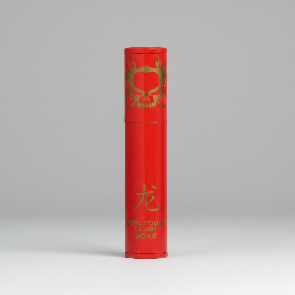 A red cylindrical cigat tube product,, decorated with gold foil graphics including a dragon motif, a Chinese character for dragon, and vertical text reading 'APRIL FOOLS 2024' and 'BOX 9'.
