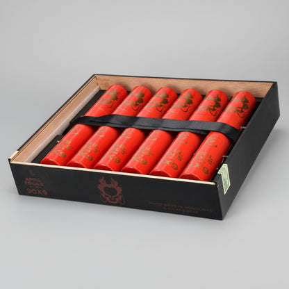 A black presentation box containing ten bright red cylindrical fireworks tubes with gold printed graphics, secured by a black strap. The box lid shows the brand name 'April Fools' and product details.