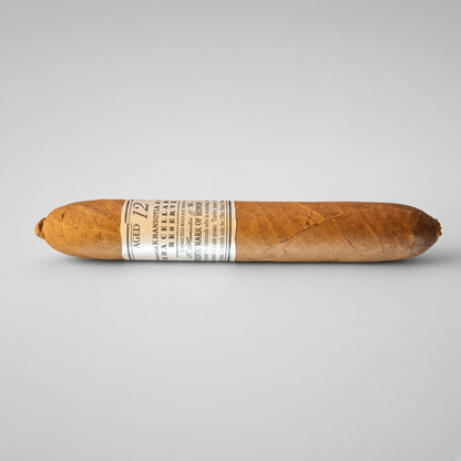A single cigar shown horizontally against a light gray studio background. The cigar is medium brown with a white paper band around the middle that reads 'Aged 12' and includes the brand name 'Pabellon' and 'Cigarro de Pabellon'.