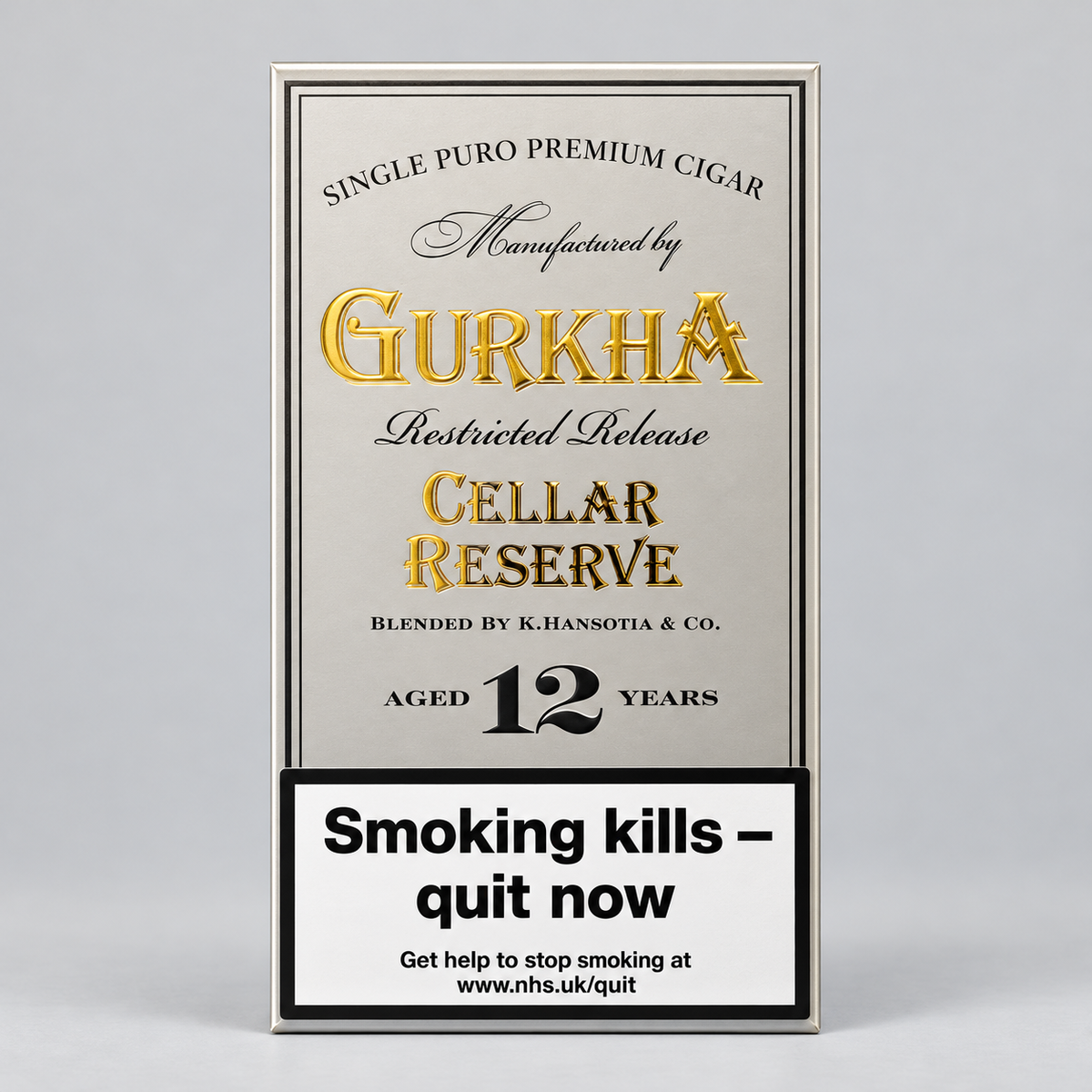 A rectangular cigarette pack label or packaging panel for Gurkha Cellar Reserve, with a silver-gray background, gold and black typography, and a white smoking-health warning box at the bottom. The product is photographed upright on a light gray studio background.