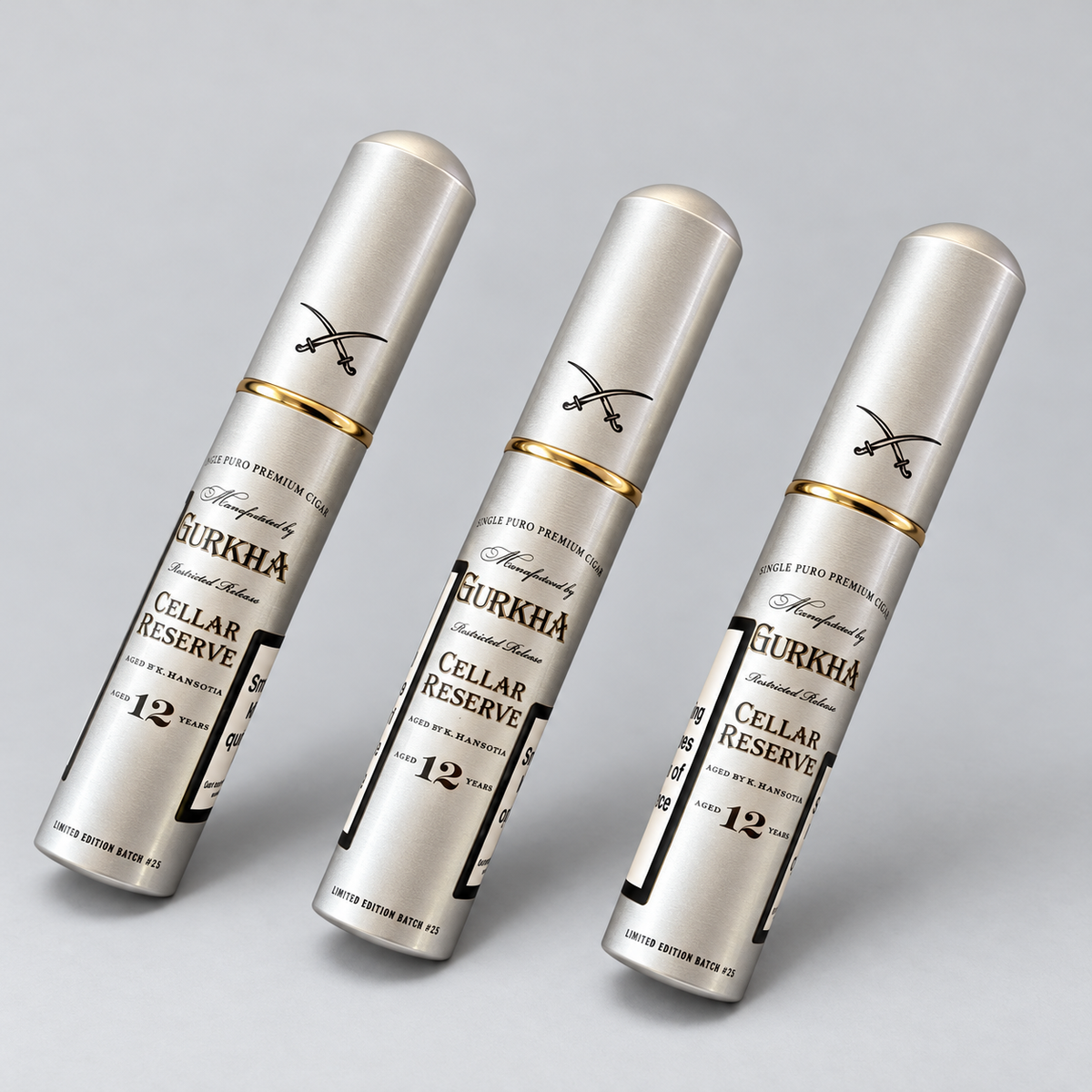 Three silver cylindrical cosmetic tubes with gold bands and black text reading 'GURKHA CELLAR RESERVE' are arranged diagonally on a light gray background.