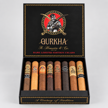 An open black Qurkha cigar box displaying eight assorted cigars in different shades from light tan to dark brown, set against a neutral light gray background.