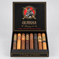 An open black Qurkha cigar box displaying eight assorted cigars in different shades from light tan to dark brown, set against a neutral light gray background.