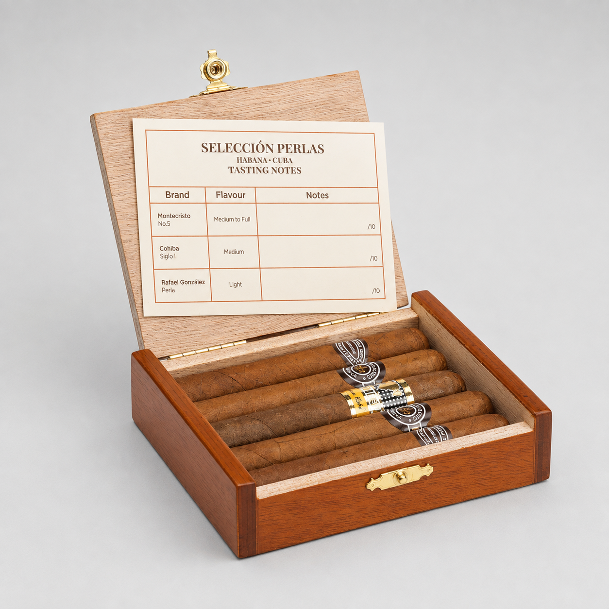 An open wooden cigar box with brass hardware on a light gray background. Inside are several cigars arranged in slots, and the inner lid displays a tasting notes card titled 'SELECCIÓN PERLAS HUMAN-CRAFT TASTING NOTES'.