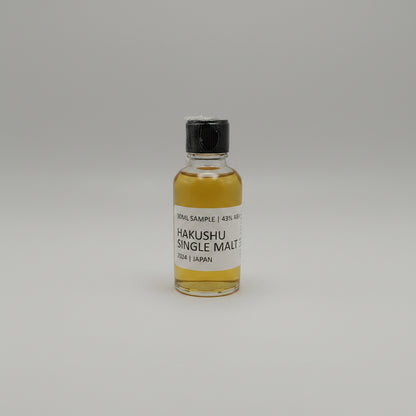 Small bottle of Hakushu Single Malt whisky sample on a gray background