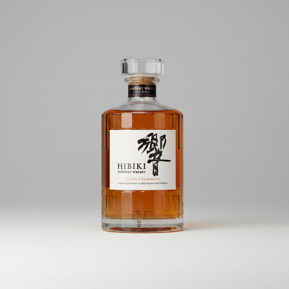 A bottle of Hibiki Suntory Whisky with a clear glass body showing the amber-colored whisky inside, a white label with black Japanese calligraphy and text, and a silver-toned cap, isolated on a white background.