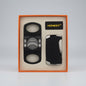 A cigar accessory gift set by Honest, including a black cigar cutter with silver accents and a black lighter with a silver side trim, presented in an orange box with a beige insert.