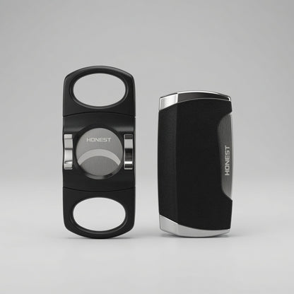 Two black cigar cutters with silver accents, shown from the front and side on a light gray background. The brand name 'HONEST' is visible on both pieces.