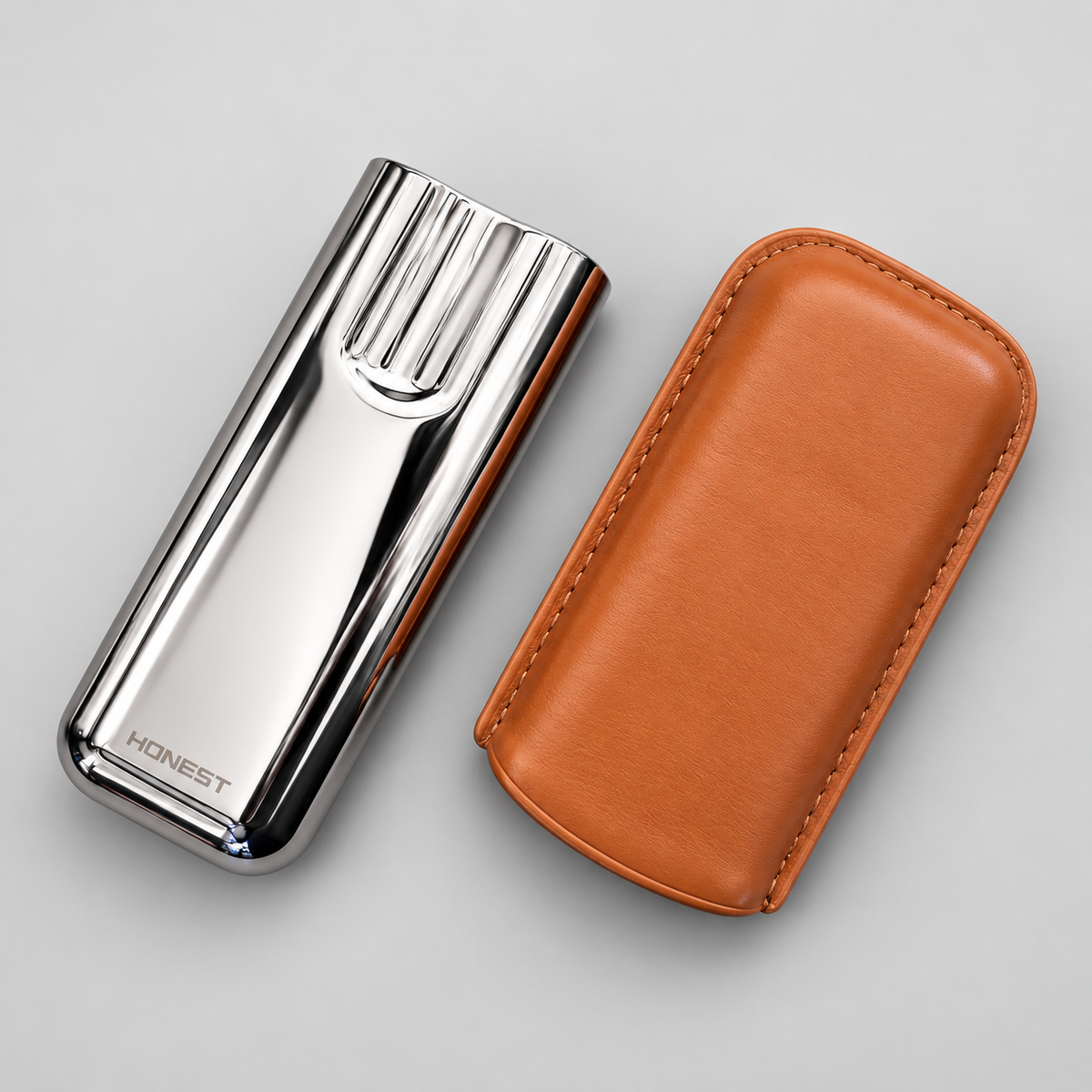 A polished silver metal CIGAR CASE with the brand name 'HONEST' engraved on it, shown next to its tan leather protective case on a light gray background.