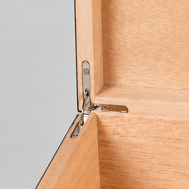 An open wooden presentation box with a light natural wood interior and a darker brown burl wood exterior. The inside lid features a black circular speaker and a silver metal button, set against a neutral gray background.
