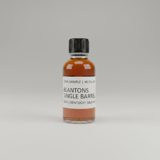 Small bottle of Blanton's Single Barrel whiskey sample on a plain background