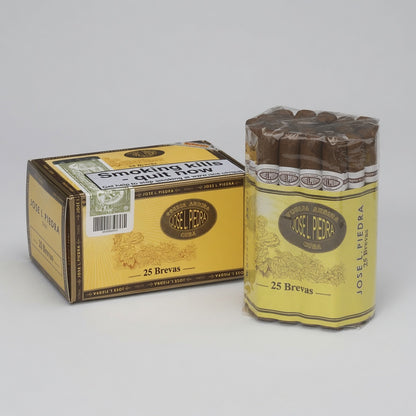 A box and a clear plastic-wrapped cylinder of cigars on a light gray studio background. The packaging is predominantly yellow and brown, with the brand name 'Josel Piedra' clearly visible on both the box and the cigar wrapper.