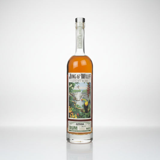 A bottle of Jung & Wulf Luxury Lines Guiana Rum No. 2, featuring amber liquid in a clear glass bottle with a detailed tropical label and a silver foil cap, set against a plain white background.