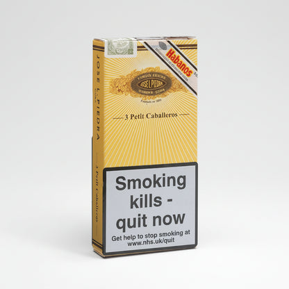 A pack of Habanos Jose L. Pedra Petit Caballeros cigarettes, featuring a yellow and gold sunburst design with a prominent grey warning label on the front.