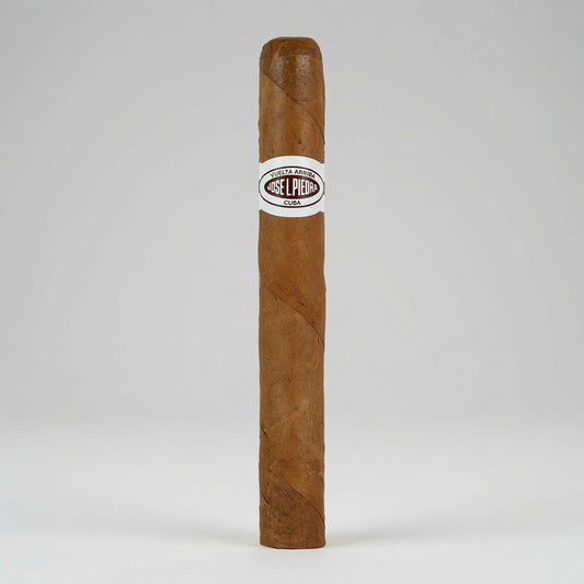 A single brown cigar standing upright against a light gray studio background, with a white band around the middle that reads 'GELPEI CIGARS'.