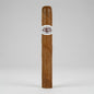 A single brown cigar standing upright against a light gray studio background, with a white band around the middle that reads 'GELPEI CIGARS'.