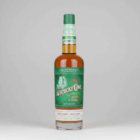 A bottle of Kentucky Owl ST PATRICKS DAY Whiskey on a white background with a reflection.
