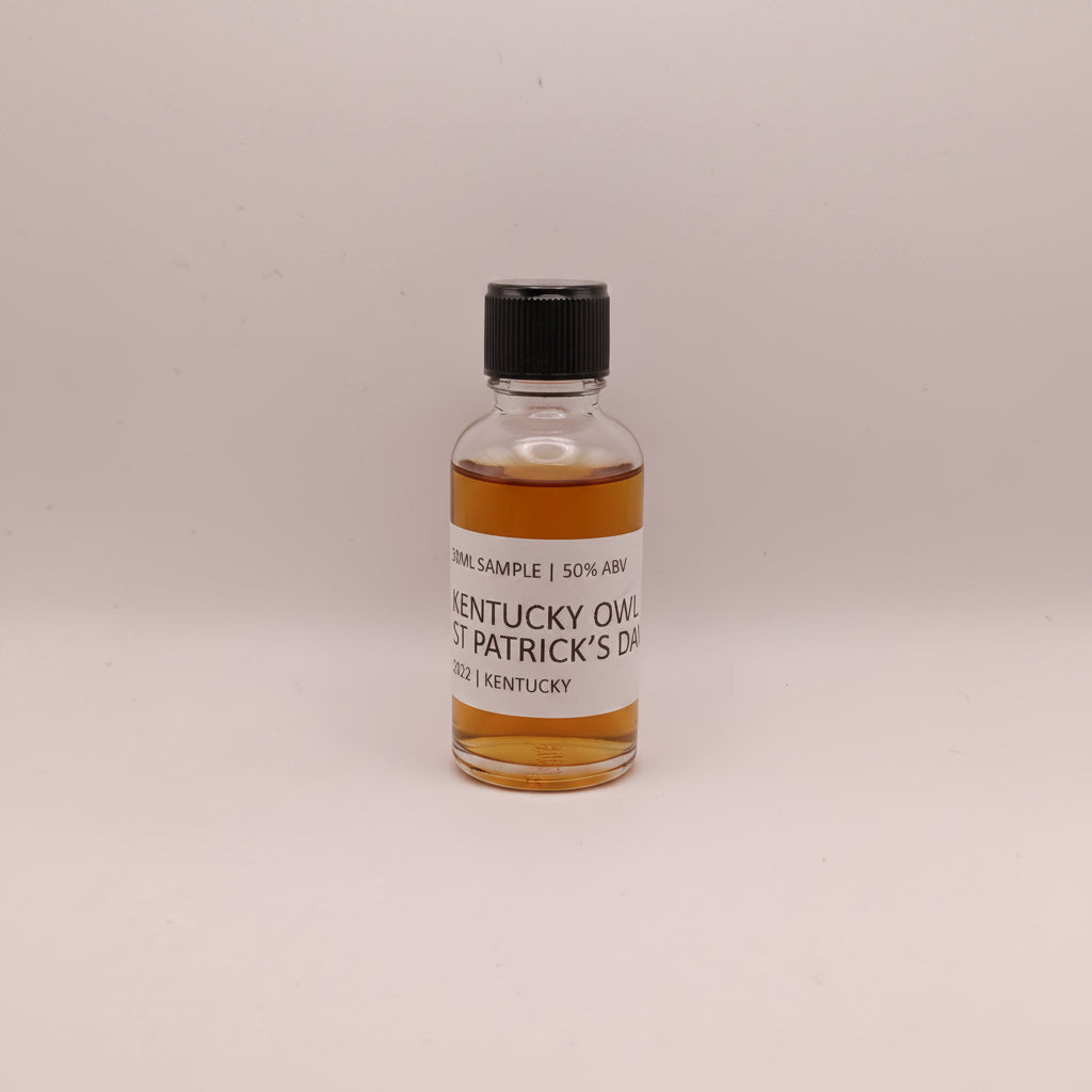 Small bottle of Kentucky Owl Whiskey with a label on a beige background