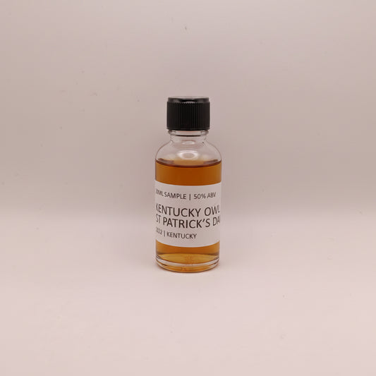 Small bottle of Kentucky Owl Whiskey with a label on a beige background
