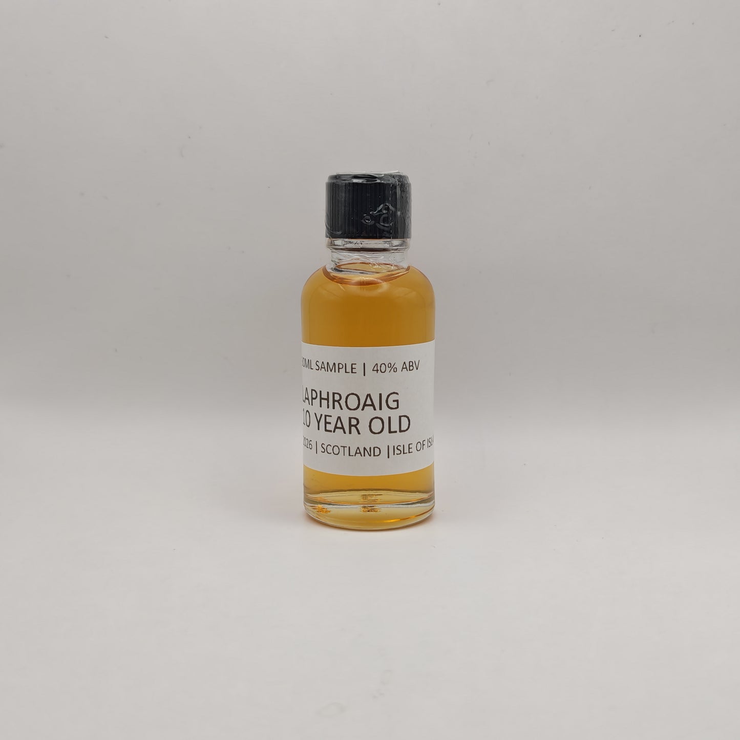 Small bottle of Laphroaig whisky sample on a gray background