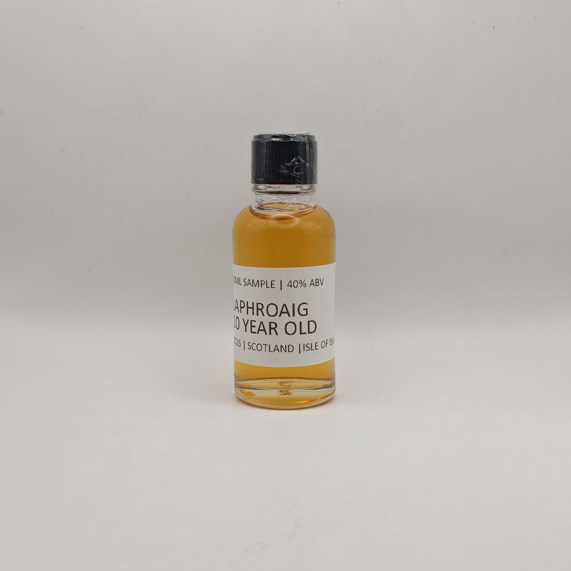 Small bottle of Laphroaig whisky sample on a gray background