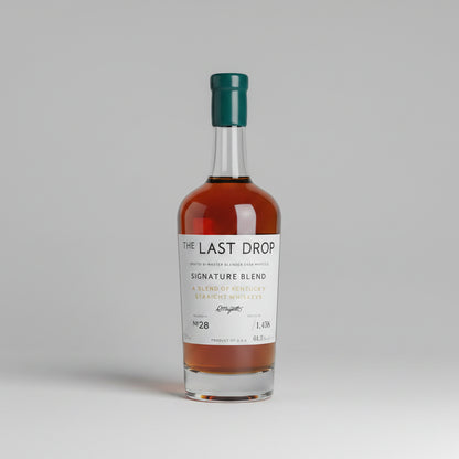A bottle of The Last Drop Signature Blend single malt whisky displayed in a wooden presentation box, with its teal gift box, inner box, small bottle, and cork stopper arranged on a wooden surface.