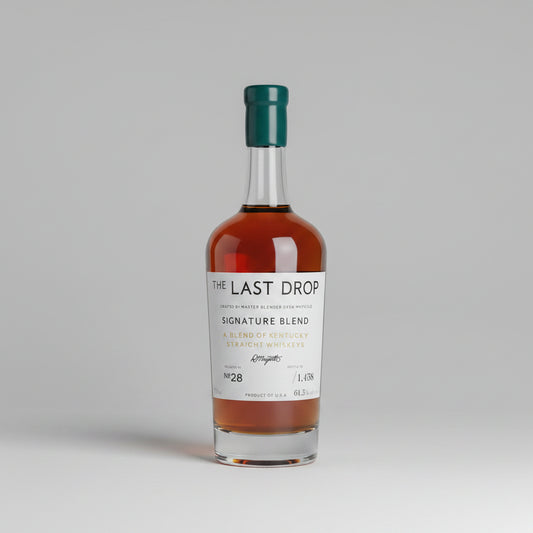 A bottle of The Last Drop Signature Blend single malt whisky displayed in a wooden presentation box, with its teal gift box, inner box, small bottle, and cork stopper arranged on a wooden surface.