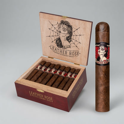 An open Leather Rose cigar box with multiple cigars inside and one single cigar standing upright beside it on a light gray studio background. The box is made of light natural wood with a dark red front panel and printed Leather Rose branding; the upright cigar has a matching red-and-black band.